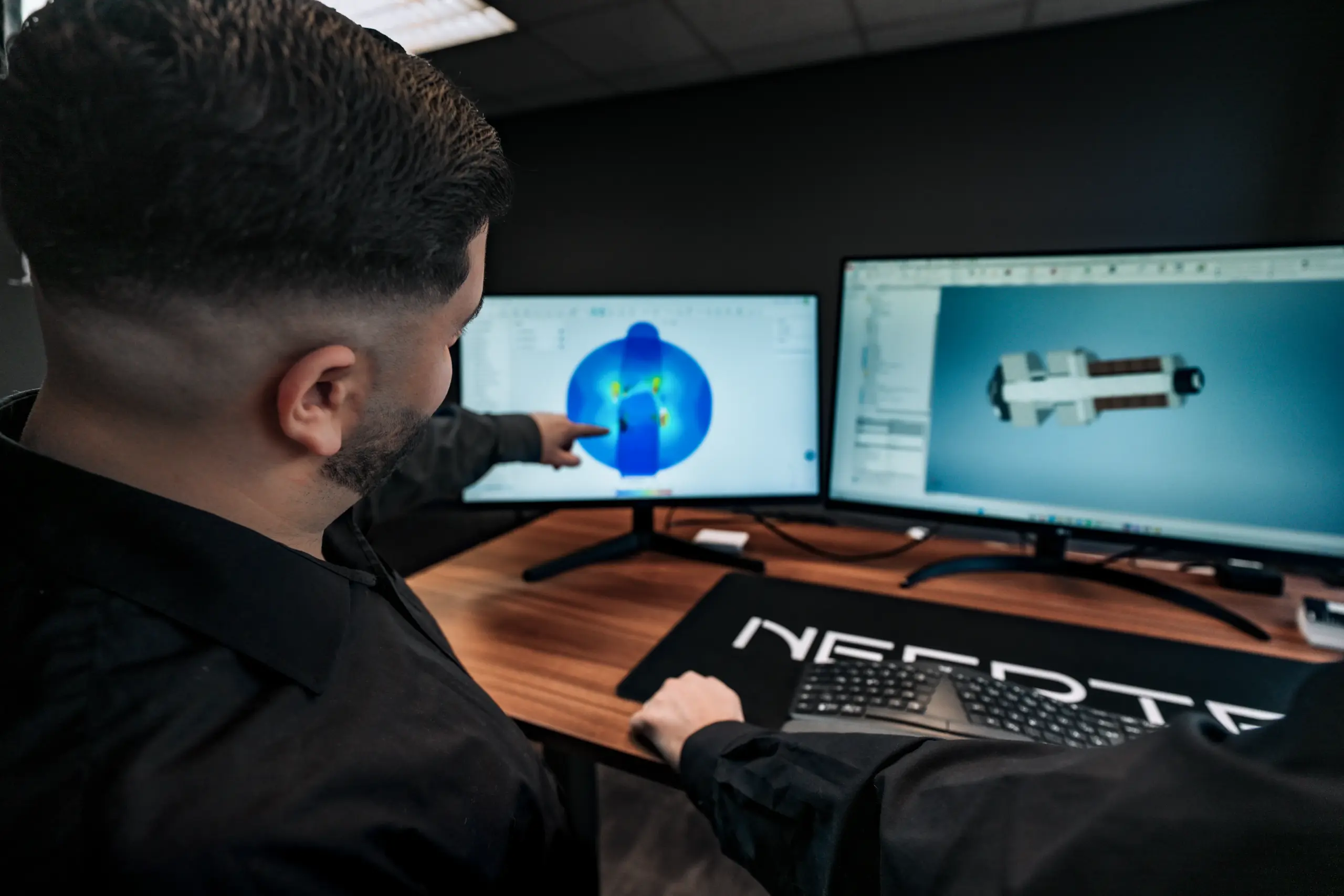 NEERTEX-Ingenieur analysiert FEM-Ergebnisse und eine mechanische Konstruktion als CAD-Modell an zwei Monitoren